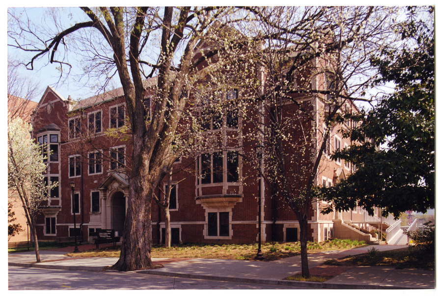 Outside shot of the D.M. Smith building. A tree about to bloom obscures part of the view.