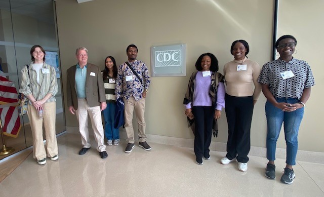 Georgia Tech students standing by a CDC plaque on a tan wall