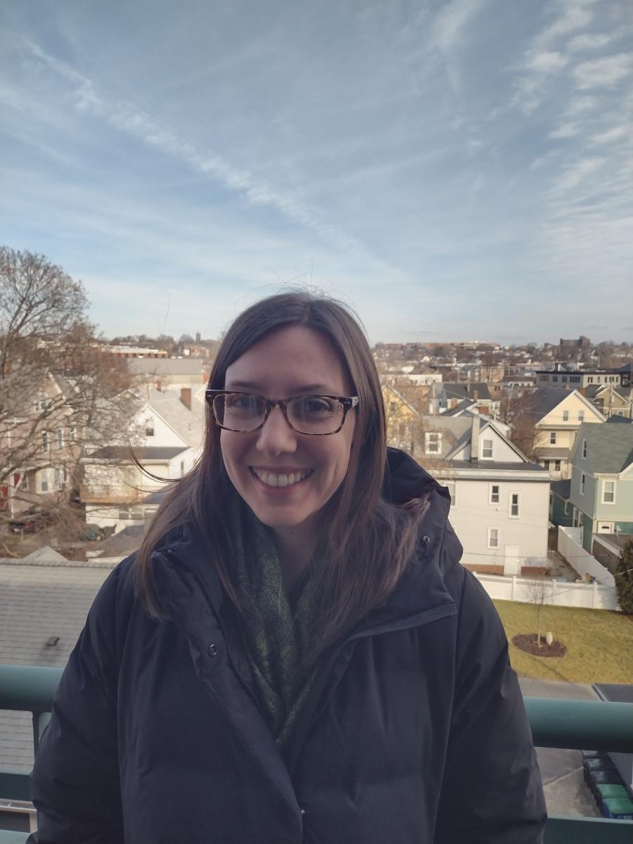 Clara Boothby standing outside, with houses' rooftops in the background.